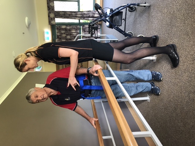 Optimum physiotherapist supporting an aged care resident during gait training