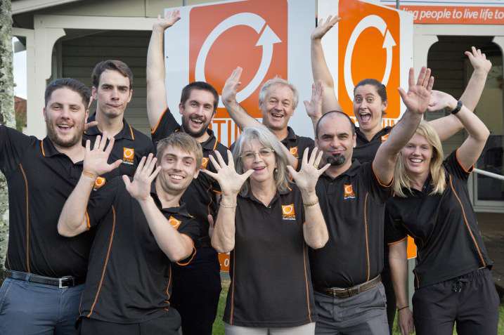 Early Optimum team members cheering together in front of the original clinic signage