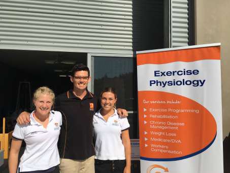 Early Optimum team members outside the original gym with an exercise physiology banner