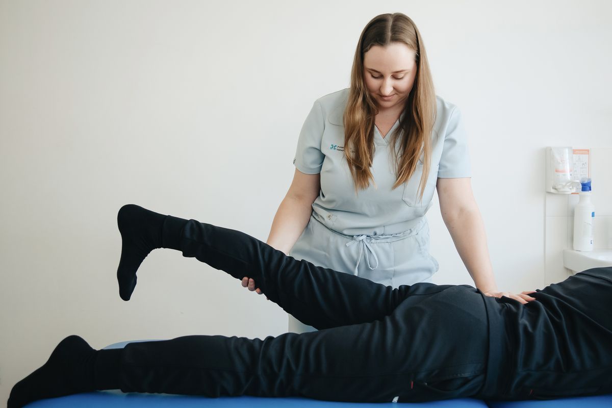 Physiotherapist stretching a patient's leg and hip during treatment