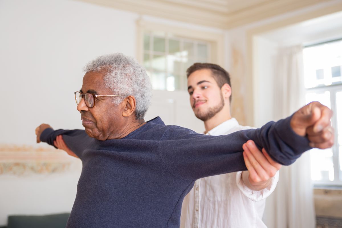 Older man doing stretching exercises with support at home