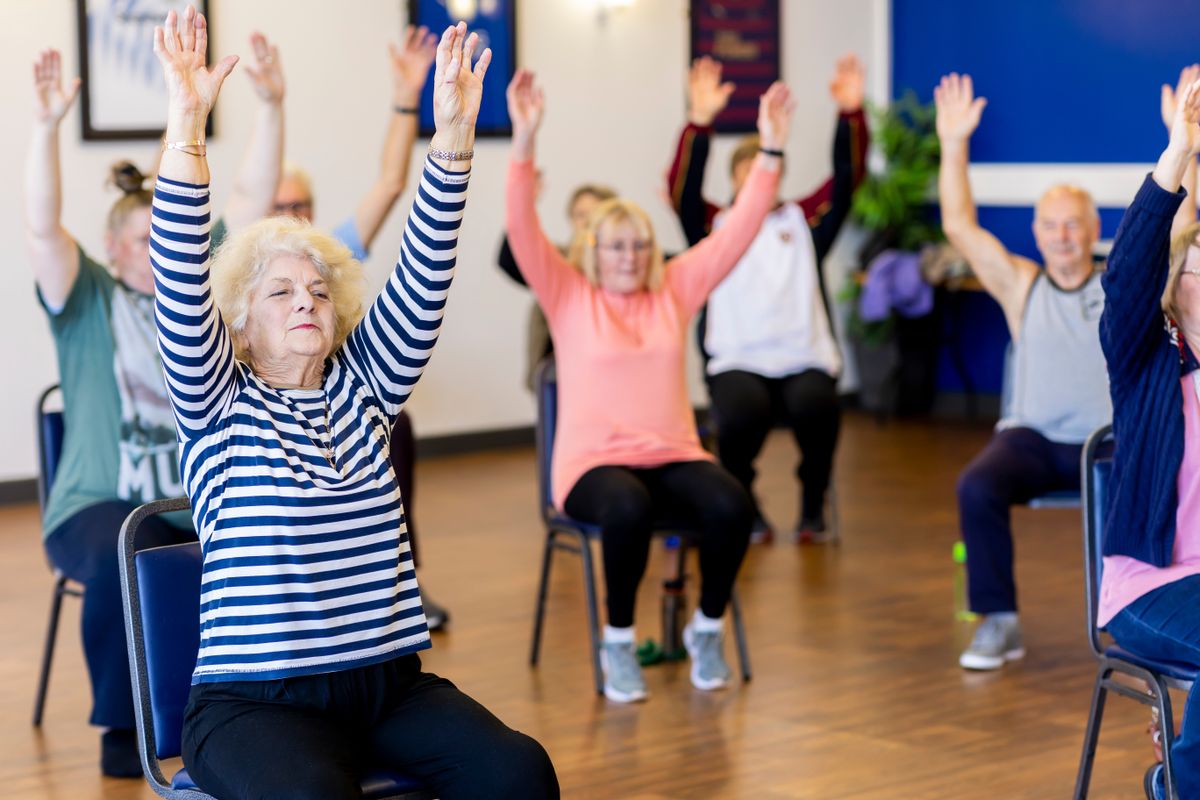 Group of older adults taking part in a seated exercise class
